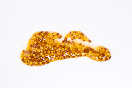 Smear of French Dijon mustard on a white background, top view.