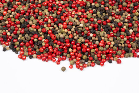 Red, green, white and black peppercorns on a white background