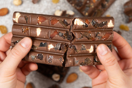Broken chocolate bar in hands close-up view from above