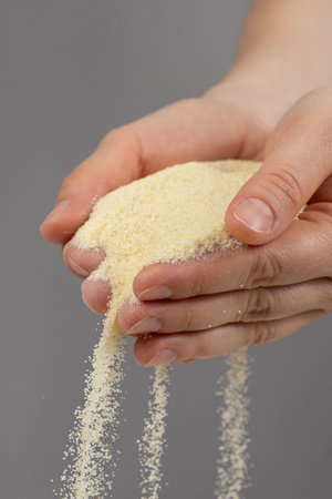 Hands pouring dry semolina durum flour uncooked organic semolina close-up gray background.の写真素材