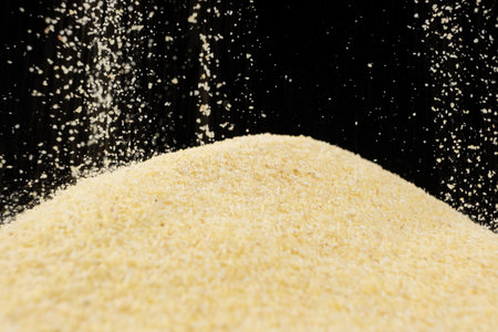 Uncooked dry semolina pour on a black background.の写真素材