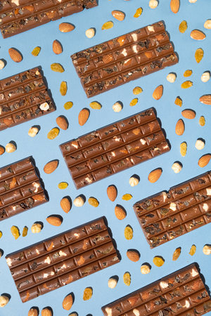 Lots of chocolate bars with nuts and raisins on a blue background top view