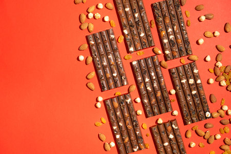 Lots of chocolate bars with nuts and raisins on a red background copy space for text.の写真素材