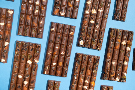 Lots of chocolate bars with nuts and raisins on a blue background top viewの写真素材