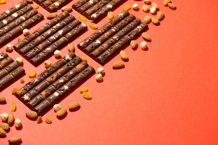 Lots of chocolate bars with nuts and raisins on a red background copy space for text.の写真素材