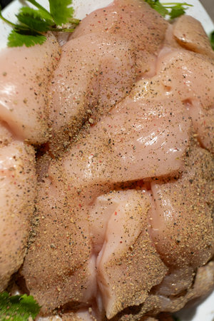 Raw chicken fillet sprinkled with spices, ground pepper mixture.の写真素材