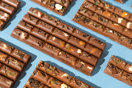 Lots of chocolate bars with nuts and raisins on a blue background.の写真素材