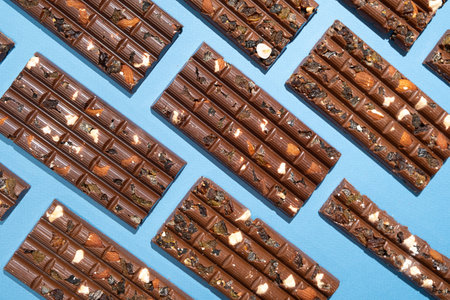 Lots of chocolate bars with nuts and raisins on a blue background top viewの写真素材