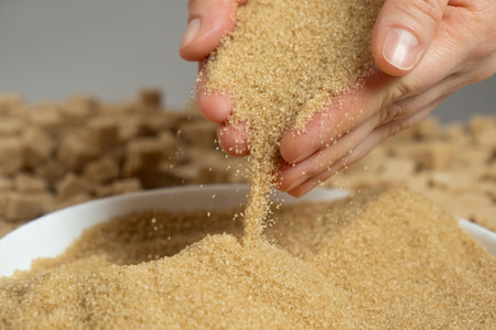 Hands pour crystalline cane brown unrefined demerara sugar.の写真素材