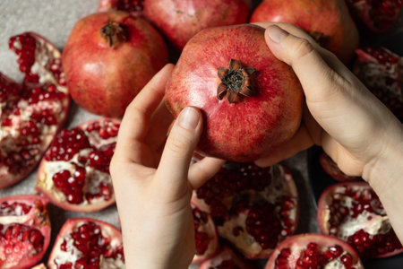 Ripe pomegranate in the hands, the concept of benefits and vitamins.の写真素材