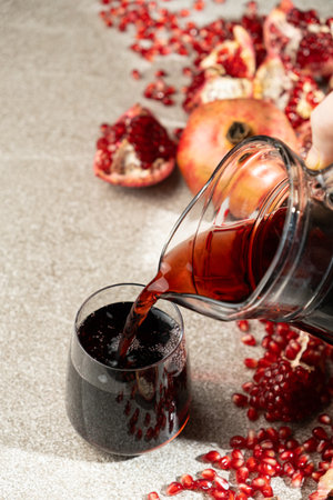 Pomegranate juice pouring from jug into glassの写真素材