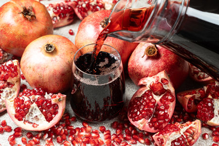 Pomegranate juice pouring from jug into glass.の写真素材