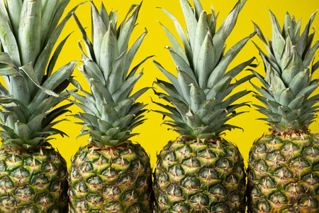 Four ripe fresh pineapples on a yellow backgroundの写真素材