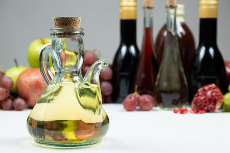 Apple cider vinegar in a vinegar cruet with spout on the background of other types of vinegars and...