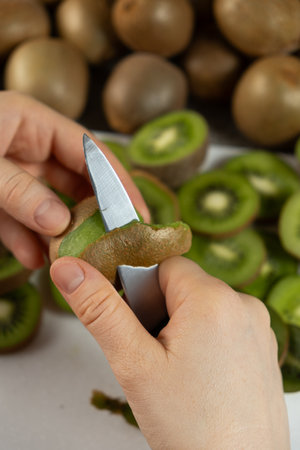 The process of peeling fresh ripe kiwi with a knifeの写真素材