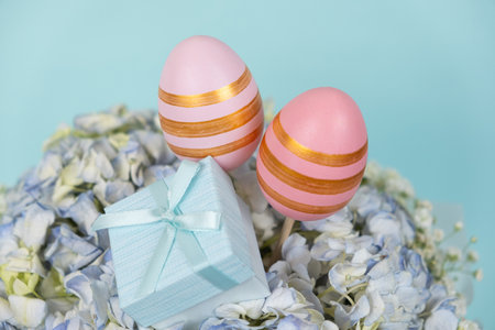 Two Easter painted eggs in a bouquet of flowers and a little gift box.