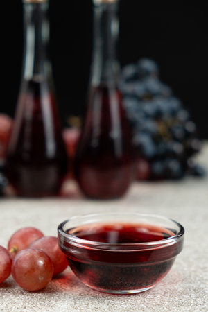 Red wine vinegar in glass vinegar bowls among grapes.の写真素材