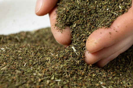Hands pour dry crushed savory seasoning.