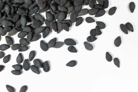 Black sesame seeds scattered on a white background macro top view.の写真素材