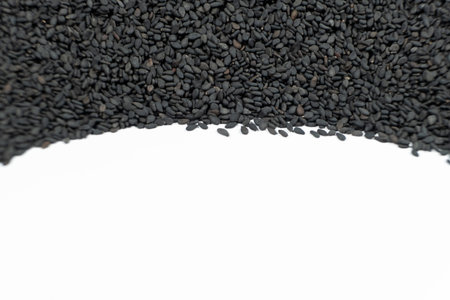 Black sesame seeds scattered on a white background place for text.