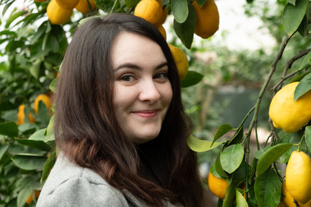 Portrait of brunette woman looking at the camera smiling in citrus garden.