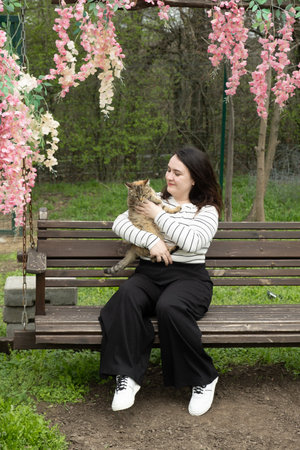 Woman holding a cat on a bench in the parkの写真素材
