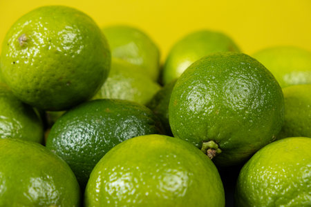Whole fresh limes fruit on yellow background close-up.の写真素材
