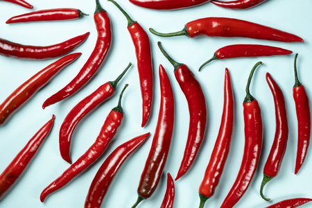 Chili peppers of different shapes on blue background, top view.の写真素材