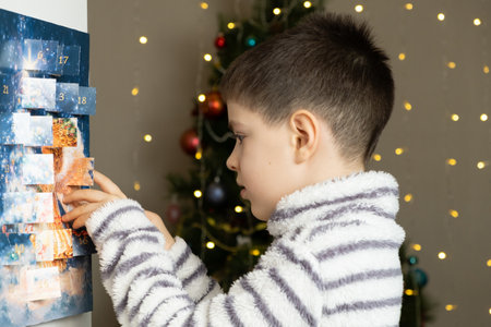 A child takes out a small chocolate from a Christmas advent calendarの写真素材