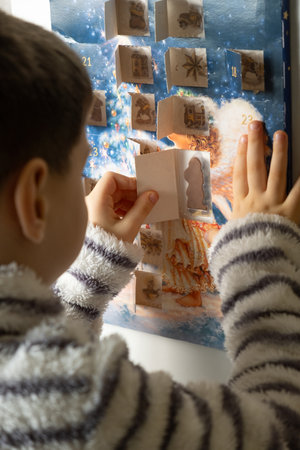 A child takes out a small chocolate from a Christmas advent calendarの写真素材