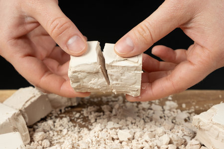 Hands Breaking Fresh Yeast Cube for Baking Preparationの写真素材