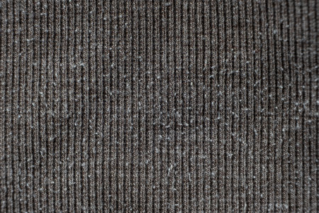 Macro texture of gray fabric with lots of pilling and damage on the surface.