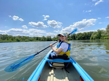 Happy woman in kayak with paddle, summer day, kayaking on the riverの写真素材