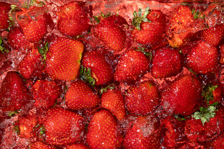 Ripe whole strawberry in water, berry splash, summer background, top view.の写真素材
