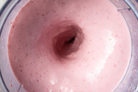 The process of making a strawberry milkshake, whisking all the ingredients in a blender
