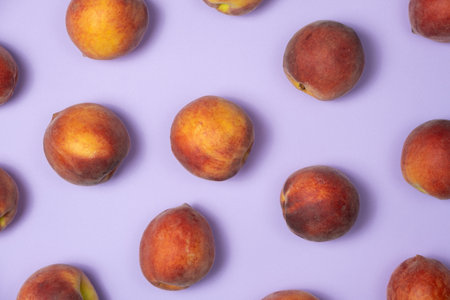 Fruity summer background whole peaches on purple background top view