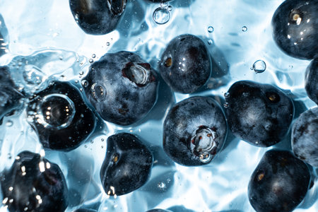 Berry background of fresh whole blueberries in water, splash of water, top view.