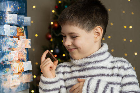 A little boy holding a chocolate Santa figurine from the advent calendar in his handsの写真素材
