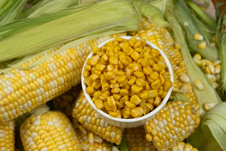 Bowl Of Preserved Corn Kernels With Fresh Corn Cobs Around
