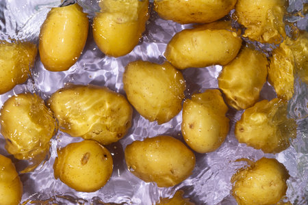 Whole Raw Potatoes In Water Top View, Splash And Ripples.の写真素材