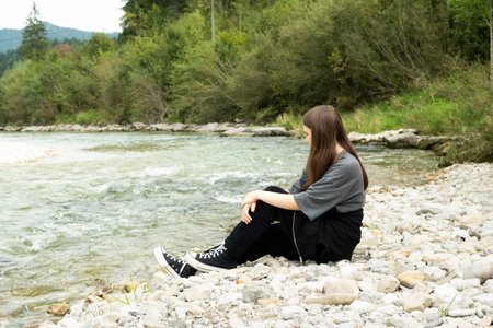Teen Girl Sitting Along the River in Nature
