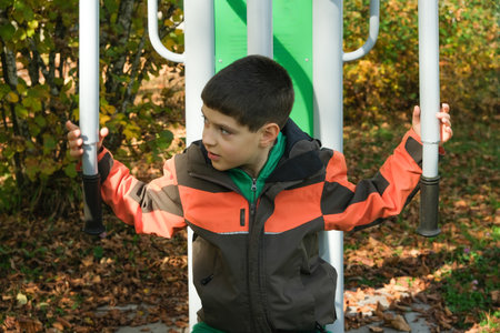 Young Boy Exercising on an Outdoor Fitness Machine in Autumn Park