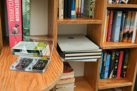 Vintage audio cassette lying among paper books on wooden bookshelf. 12 October 2025, Lunz am See, Austriaのeditorial素材