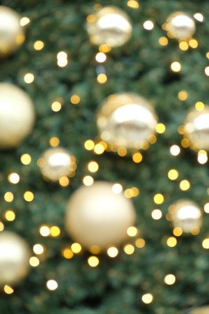 Abstract Holiday Wallpaper. Blurred Fir Tree Decorated with Shiny Gold Baubles.