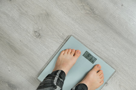 Top View of Bare Feet Standing on Modern Digital Bathroom Scales. Copy Space for Textの写真素材
