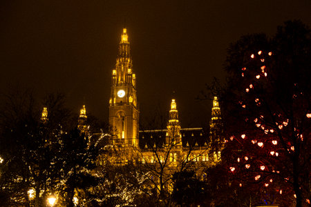 Illuminated gothic town hall tower in Vienna at night with festive lights during Christmas season.の写真素材