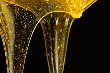 Luxury golden honey dripping on black backgroundの写真素材
