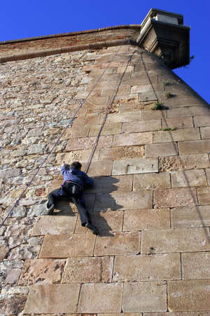 A person climbing a stone wall in Montjuic,Barcelona.の写真素材