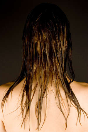 The back of a young woman's head with wet hair against a plain background.の写真素材