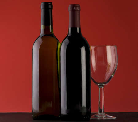 Two Bottles of red wine with a wine glass on a plain backgroundの写真素材